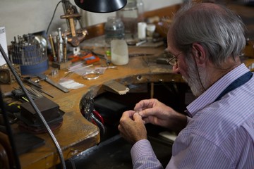 Goldsmith working at desk in workshop