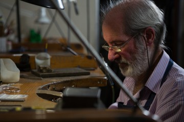 Goldsmith working at desk in workshop