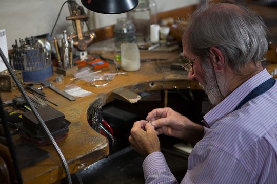 Goldsmith working at desk in workshop