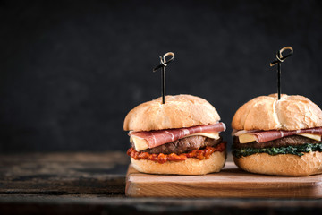 Beef burgers with prosciutto served on the wooden board,blank space