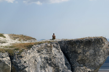 Girl in a dress sitting on a rock. White rock Crimea