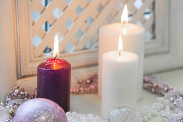 Obraz na płótnie Canvas Burning candles and pink christmas decorations on a white wooden background