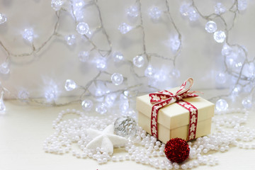 Gift box with white christmas decorations on a white wooden background