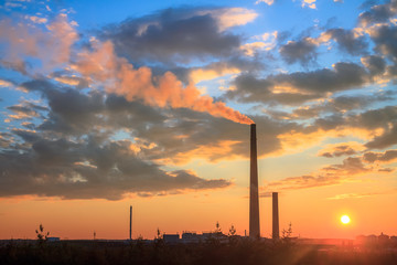 View of a smelter stack of a nickel plant showing the emission on the air with sunset sky as as...