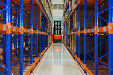 Electric forklift between large shelving in a modern storage building.