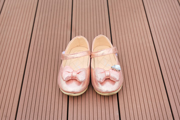 Pair of fashion princess shoes on wood plank background. Baby shoes.