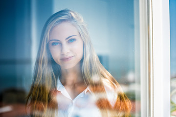 Young thoughtful woman looking through the window