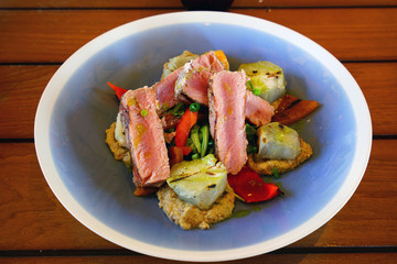 A healthy and hearty salad with sliced seared tuna, eggplant, and sweet potato