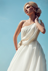 Fototapeta na wymiar Beautiful bride with fashion wedding hairstyle - on sky background