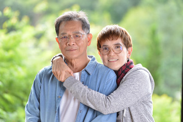 Fototapeta premium Portrait of happy romantic senior couple looking at the camera on green nature background
