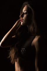 Closeup portrait of lovely woman with lush hair in black lingerie posing in the shadow