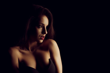 Glorious young woman in black bra with naked shoulders posing in the shadow