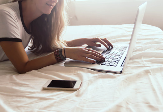 Attractive girl using computer on the bed.