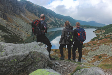 Troje młodych turystów na szlaku górskim podziwiający widoki - obrazy, fototapety, plakaty