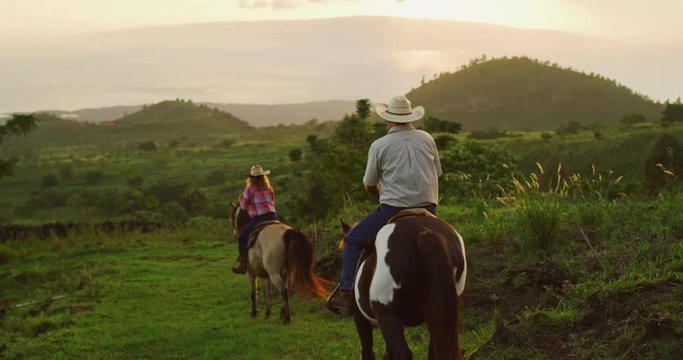 Couple horseback riding together at sunset