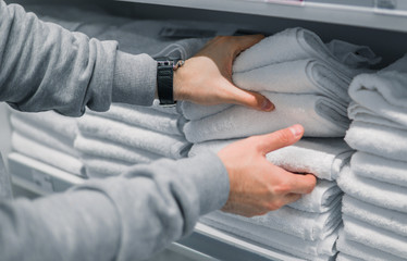 Male Customer inspecting and buying towels in supermarket. White clean towels