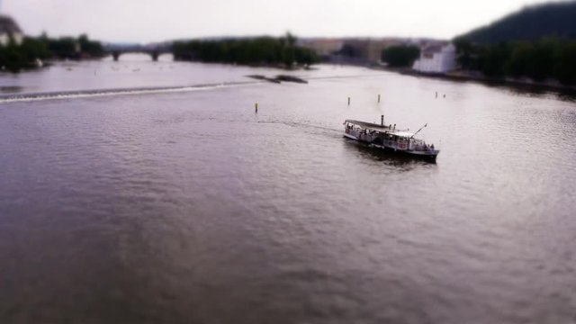 Miniature Boat turning around on Vltava river at the Charles Bridge  in Prague (Tilt-shift)