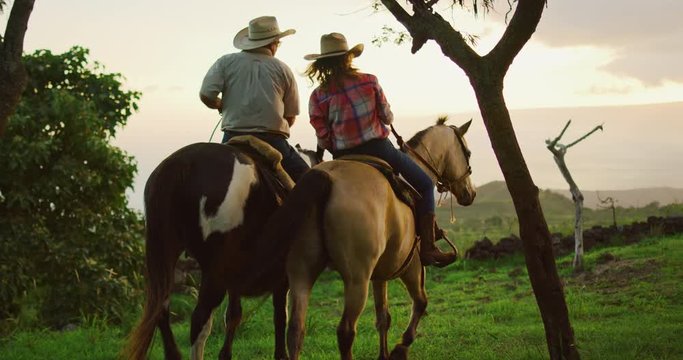 Couple horseback riding together at sunset