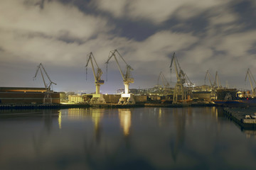 Monumental Cranes at sunrise in Shipyard. Night activity at the naval factories surrounding the city of Bilbao, Spain.
