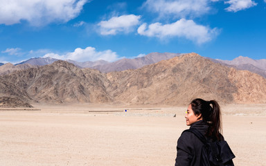 Portrait image of a beautiful Asian woman tourist standing in front of mountain and blue sky background
