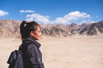 Fototapeta premium Portrait image of a beautiful Asian woman tourist standing in front of mountain and blue sky background