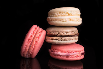 Sweet colorful french macarons, macaroons on a black background, chocolate,raspberry,vanila.