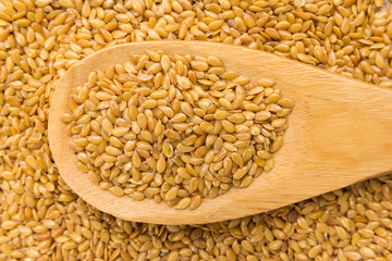 Golden Flax seed. Grains in wooden spoon. Close up.