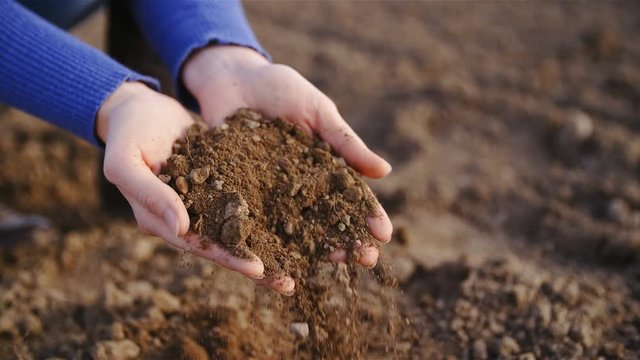 Hands dropping farm field soil close up slow motion 4K