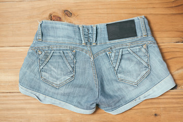 Female blue torn jeans shorts on old wooden background