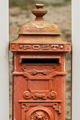 An old red vintage mailbox on a cloudy day