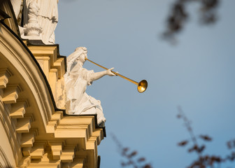 Stone figure with a golden trumpet sitting on an old building