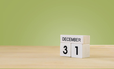 31 December wooden cube calendar on wood surface with copy space ,green blackground
