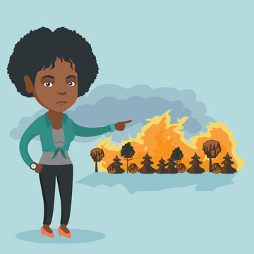 Young african woman pointing at the forest in fire