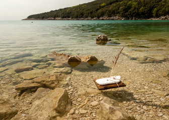 A child's handmade boat drifting in a small bay