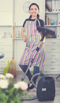 Cheerful girl vacuum cleaning floor