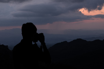 Sihouette a man take a picture at mountains background