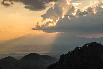 the sun shine through clouds in sunset time among mountains