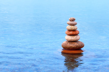 Fototapeta na wymiar Pyramid of colorful, balanced stones on the sea background. Concept of harmony and balance