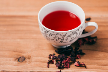 Red hot hibiscus tea in a glass mug on a wooden table