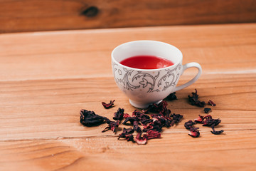 Red hot hibiscus tea in a glass mug on a wooden table