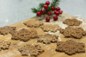 Christmas star-shaped cookies stacked on a wooden board crushed with flour sprinkled with green spruce and red cranberries