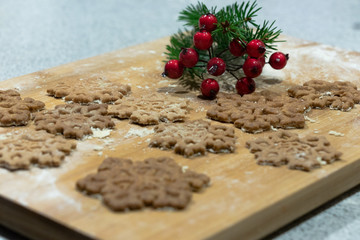 Christmas star-shaped cookies stacked on a wooden board crushed with flour sprinkled with green spruce and red cranberries