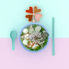 noodle clear soup with pork in a blue bowl and seasoning.