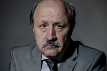portrait of sad and depressed senior mature business man on his 60s suffering depression looking lost and thoughtful wearing necktie