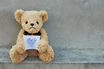 Bear hold paper that has blue heart.