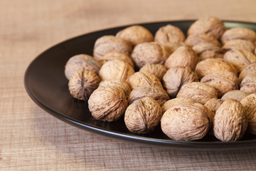 Walnuts on a black plate and on a wooden table