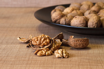Walnuts on a black plate and on a wooden table