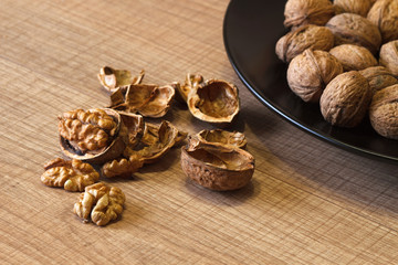 Walnuts on a black plate and on a wooden table