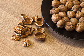 Walnuts on a black plate and on a wooden table