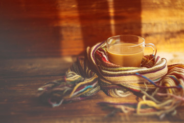 small and big red mug wrapped in a blue scarf and standing on the table against the background of a winter window / warming atmosphere for hanging out